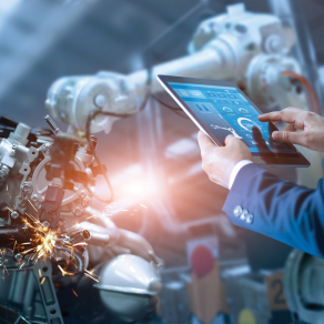 Engineer using software to monitoring robot arm welding metal. 