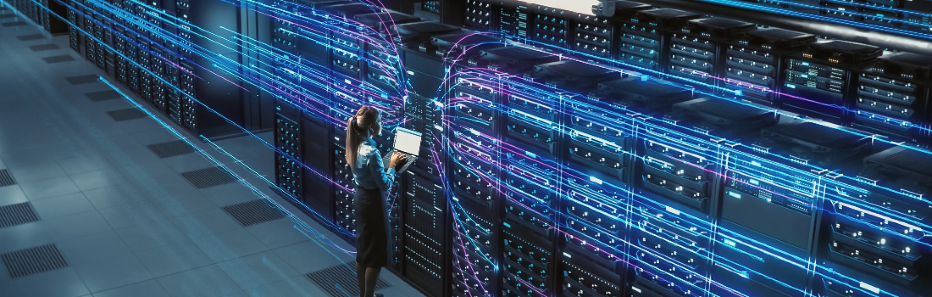 Big data center with female Chief Technology Officer using laptop standing in warehouse managing servers. 