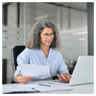 Researcher on a laptop preparing paper work for grant submission. 