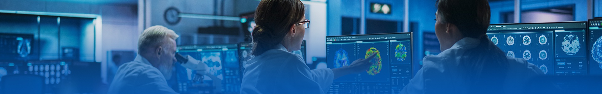 Researchers collaborating and reviewing brain scan on a screen. 