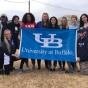 Students on an alternative break trip to the Louisiana wetlands pose with a blue UB flag outside of a service site. 