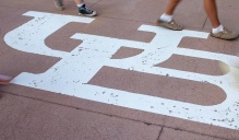 Students feet walking by white interlocking UB symbol onground.
