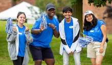 Smiling student leaders pose together with pompoms.