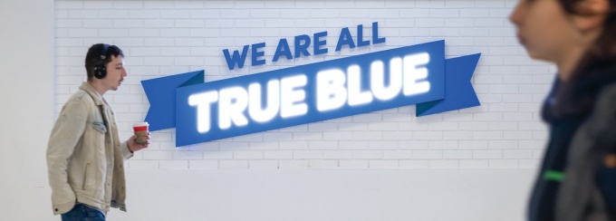 Students walking by the True Blue sign in the Student Union. 