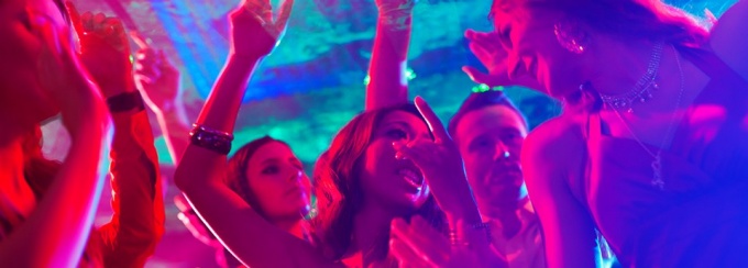 Students dancing at a party with purple and turquoise lighting. 