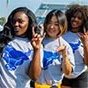 Three students showing the Horns Up hand signal at UB Stadium. 