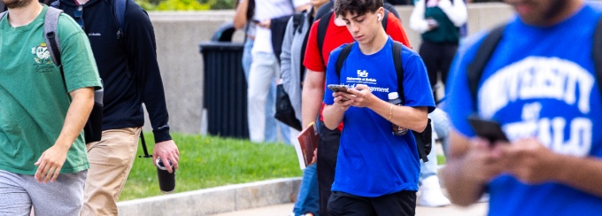 students on their phones walking on the Spine. 
