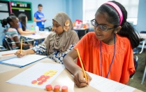 Female student working on a math test at a desk in a classrom. 