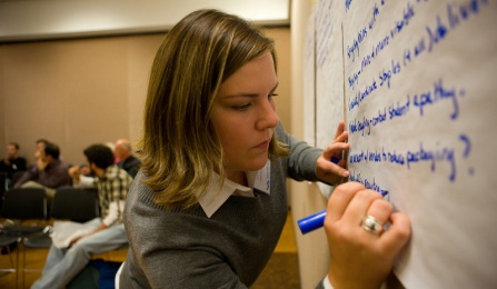 female student writing on whiteboard. 