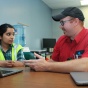 Student Manimanjari Vemula talks with Christopher Holzmann of Sumitomo Rubber USA at a desk. 