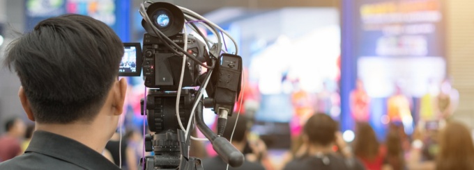 Man behind a camera filming a media event. 