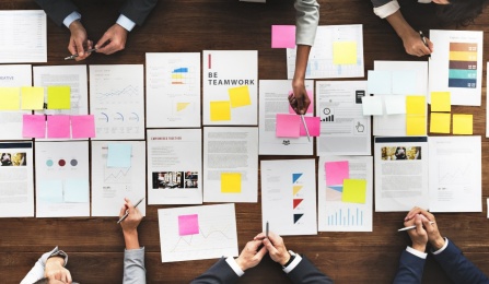 Bird's eye view of business people sitting at a table and looking at papers. 