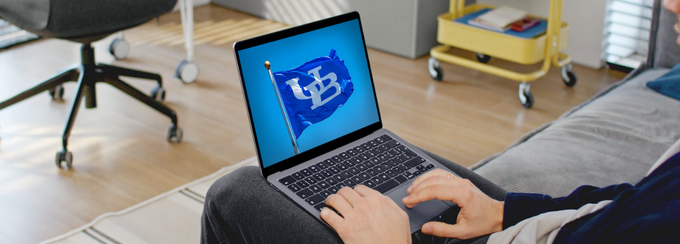 Person sitting down with laptop looking at the screen showing UB flag representing online UB courses. 