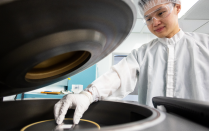 Student dressed in cleanroom outfit preparing a semiconductor wafer. 