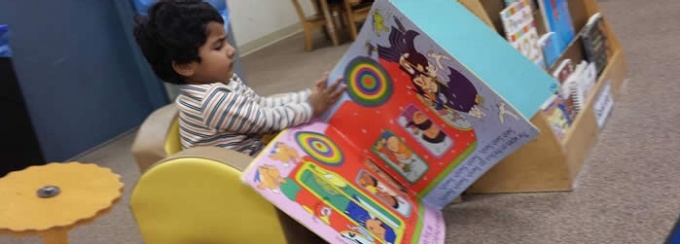 Photo - toddler reading a big book. 