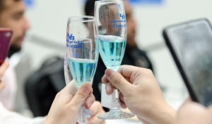 Graduating students share a "cheers" with their commemorative champagne flutes and custom blue champagne. 