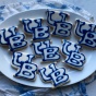 A number of UB cookies sit on a plate. One has a bite already taken out of it. 