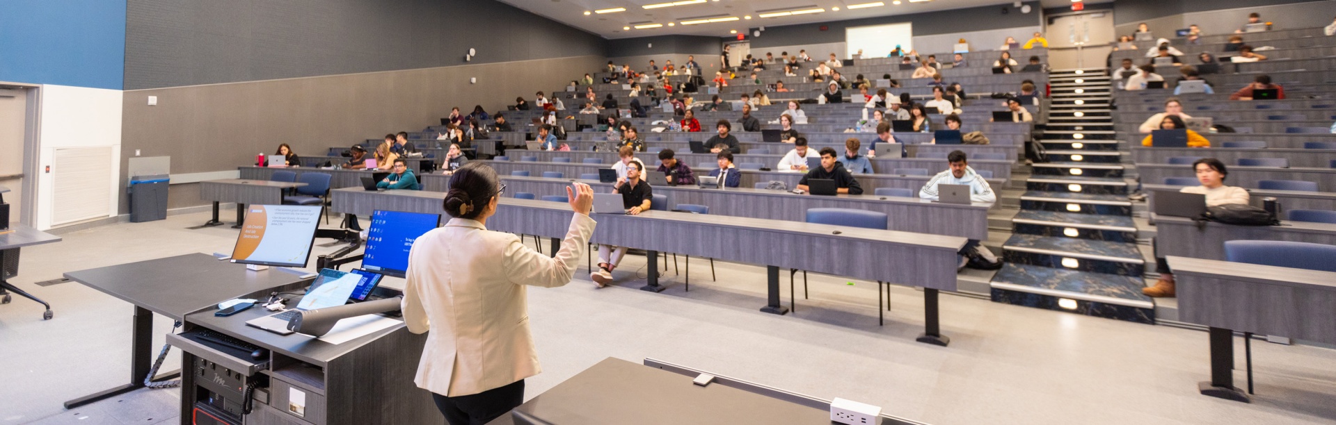 A teacher faces a large lecture hall. 