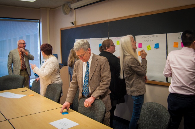 UB Provost Charles Zukoski joins in an exercise where faculty members write "wish list" items for email on post-it notes and categorize them by type of feature on large poster sheets. 