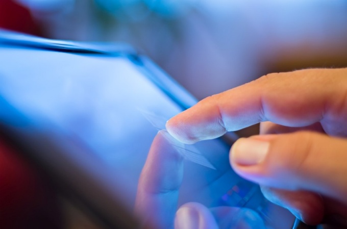 A finger extends to touch manipulate the screen of a tablet. 