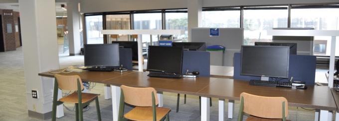Research stations in a computing site are located near a Library Reference Desk and have a Research name tag attached. 