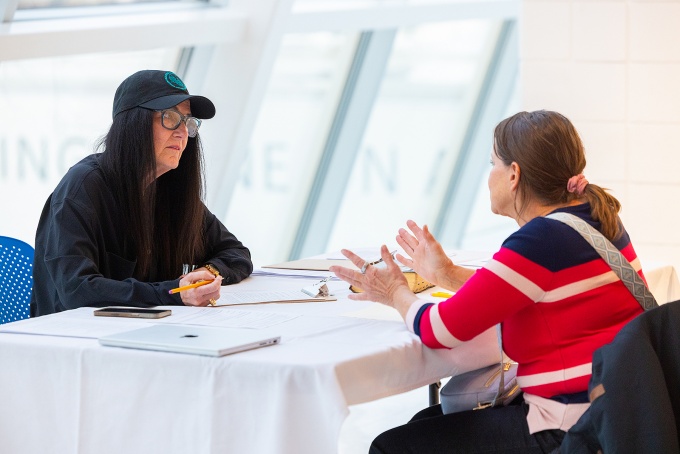 Two women sitting at a table talking. 