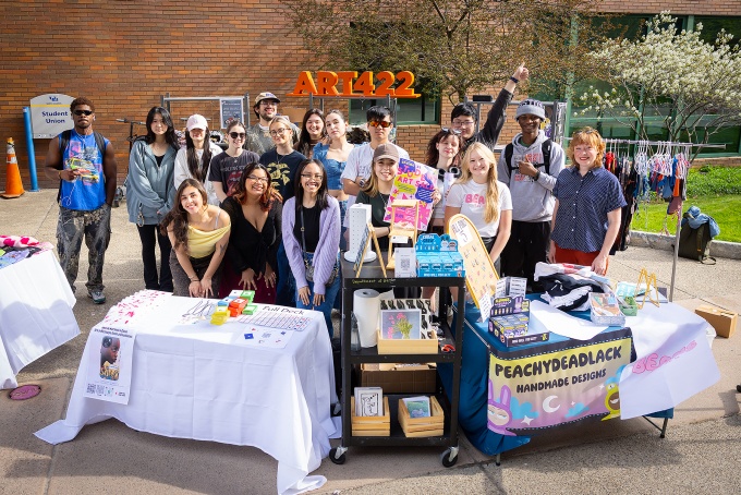 Group of UB students at tables willed wiht artwork. 