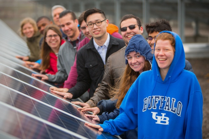 Group of people, eaching touching a solar panel. 