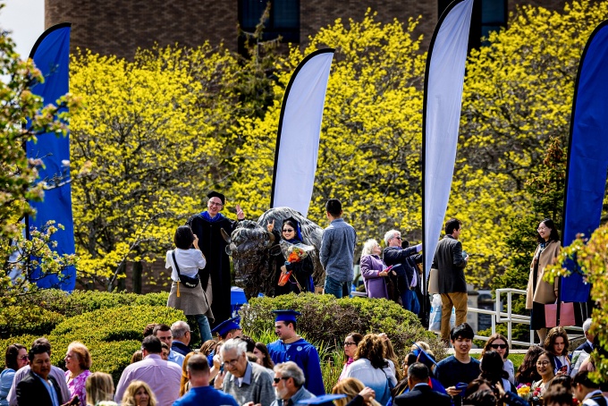 New graduates pose outside the UB bison statue. 