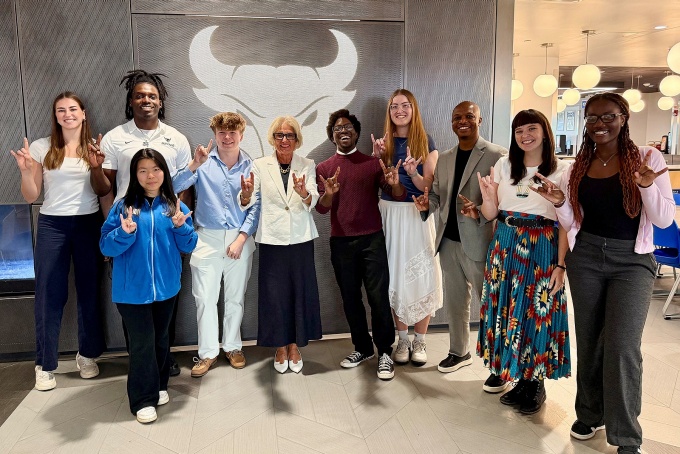 UB President Caroline Attardo Genco giving the UB "Horns Up" hand gesture with students. 