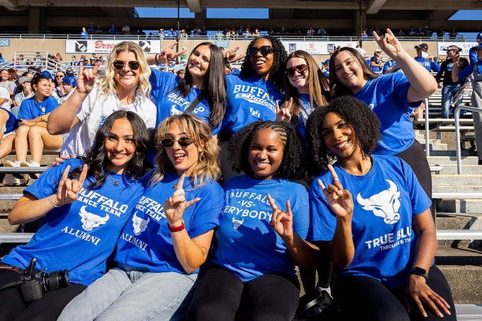 UB students flashing the "Horns Up" sign and wearing blue UB Bulls T-shirts. 