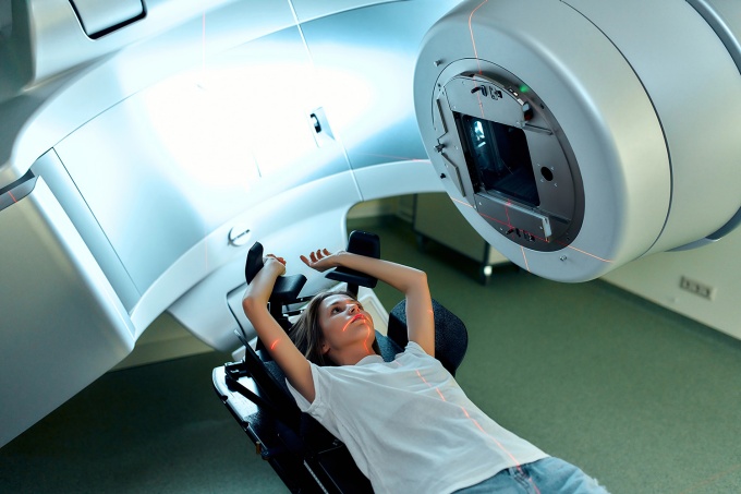 A young woman going through a radiation machine in a medical setting. 