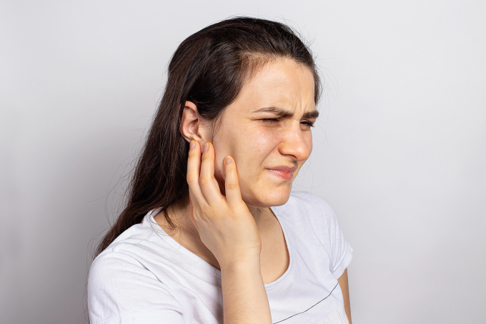 Woman in pain holds her hand to her jaw. 