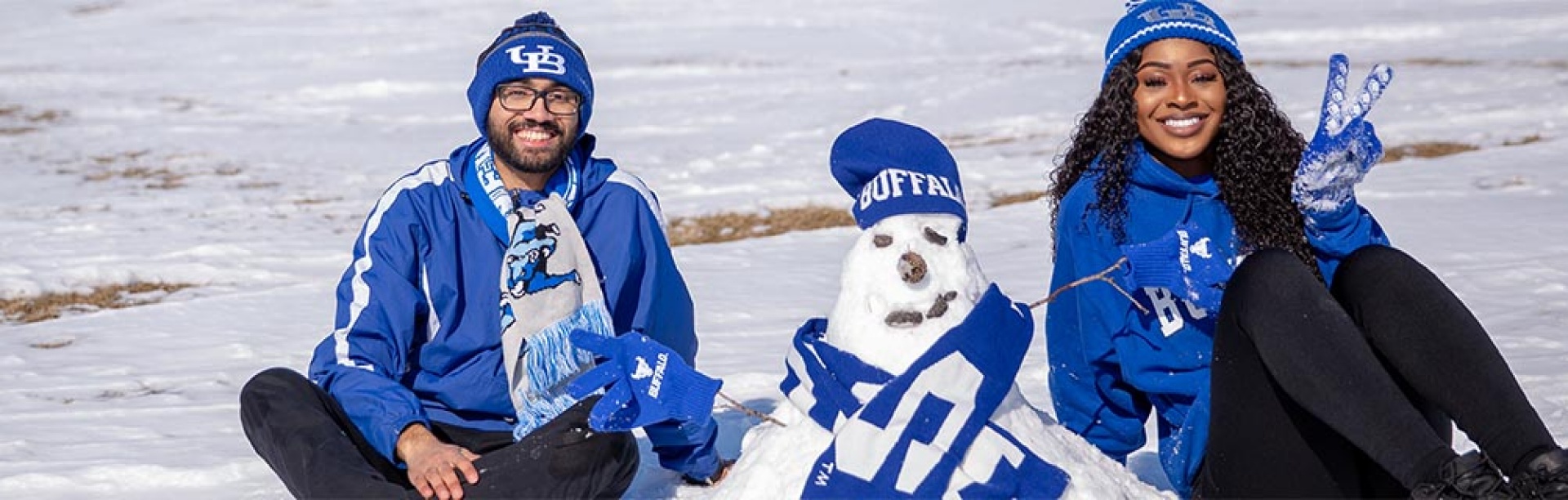 Two students posing with a snowman wearing UB gear! 