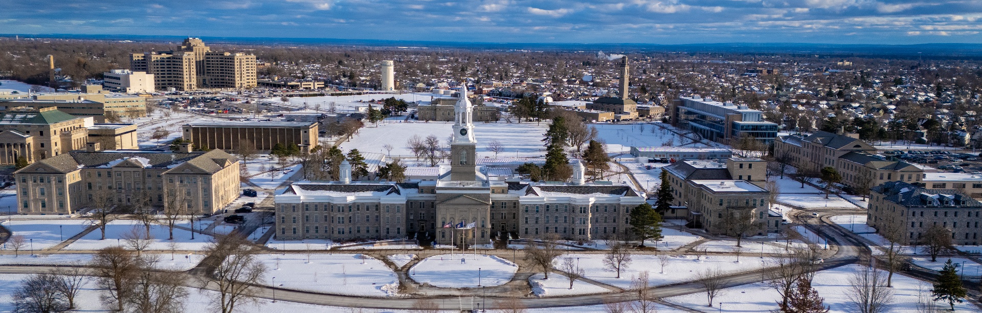 People working in the Student Union while others walk through the snow on the promenade on UB's North Campus. 
