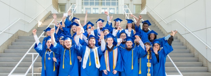 Students standing on stairs in caps and gowns. 