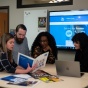 Marketing and Communications staff discuss projects in the office. 