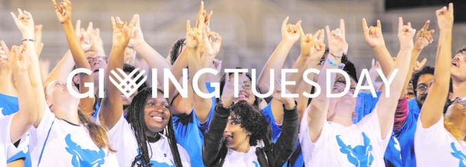 UB students in blue and white shirts give "horns up" hand signal. White text that says "Giving Tuesday" is imposed as a white overlay. 