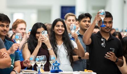 UB graduates toasting wine glasses. 