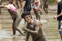 students and others playing volleyball in mud. 
