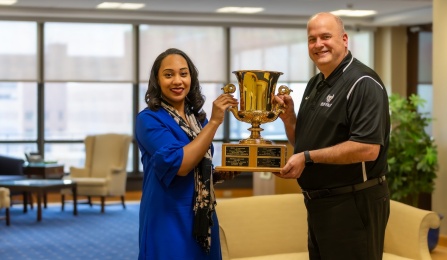 Jenell Spitale and Brian Hamluk holding a large trophy. 