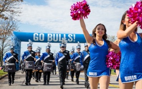 The UB Marching Band and the cheer team lead the way through the annual homecoming parade into UB Stadium. 