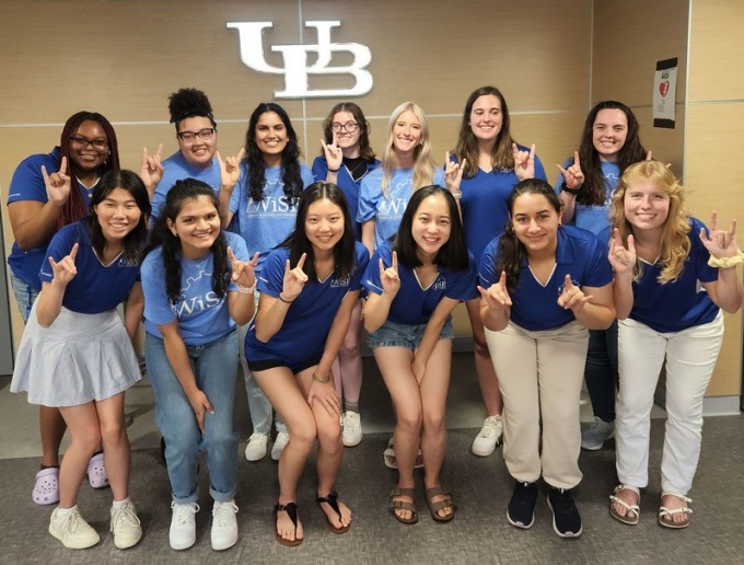 UB women in science and engineering student ambassadors pose with the UB horns up hand gesture. 