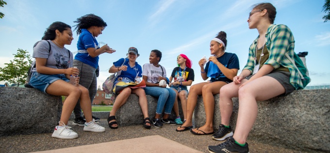Students having a discussion while seated on outdoor benches. 