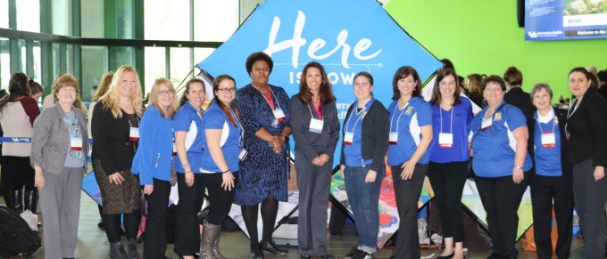 Members of the Women in STEM Cooperative, most wearing UB blue polo shirts, pose for a photo in the Student Union. 